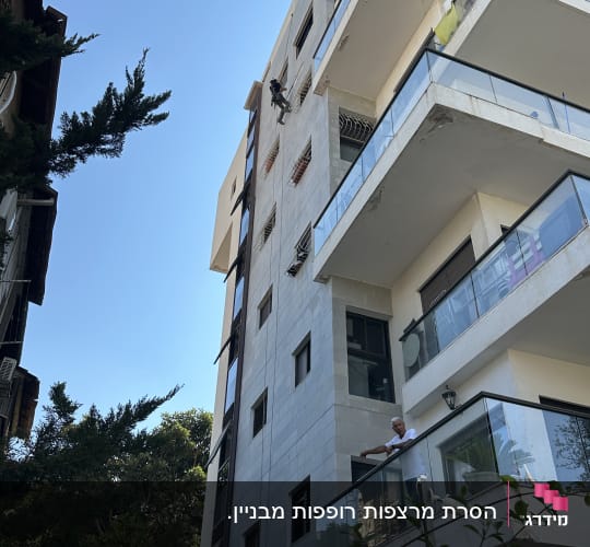 אדם עובד על בניין גבוה עם ציוד טיפוס
